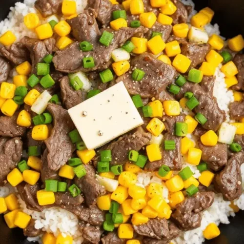 A skillet of Beef Pepper Rice with seasoned beef, rice, sweet corn, green onions, and a melting butter cube on top.