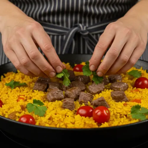 A chef garnishing a vibrant paella with fresh herbs, likely inspired by Terra Massoud's recipe.