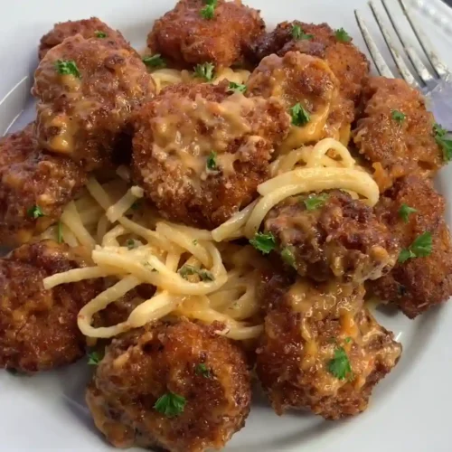 A plate of crispy Boom Boom Shrimp served over creamy spaghetti, garnished with fresh parsley.