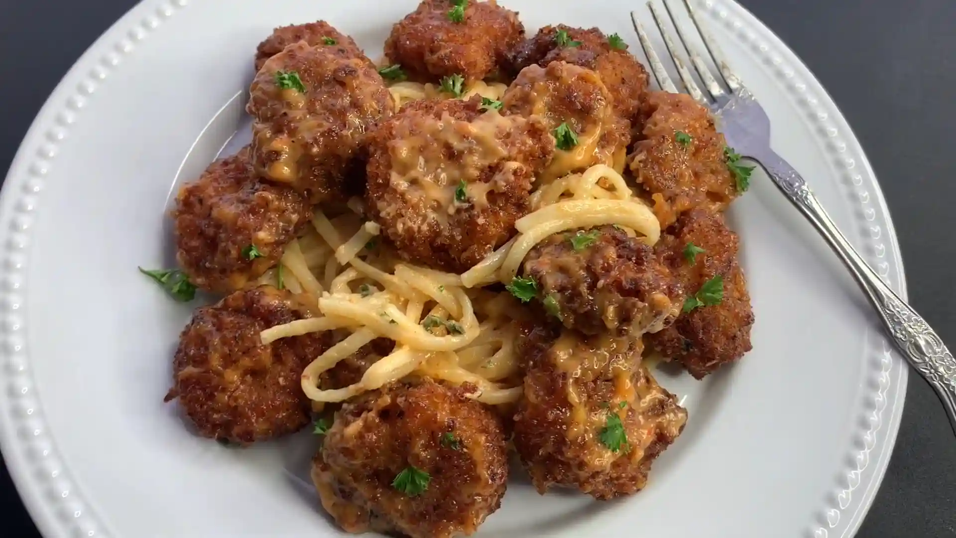 A plate of crispy Boom Boom Shrimp served over creamy spaghetti, garnished with fresh parsley.