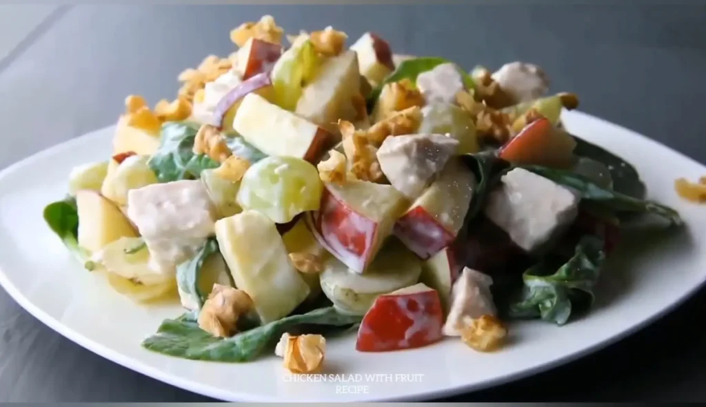 Colorful chicken salad with apples, grapes, walnuts and leafy greens on a white plate - Ensalada de Pollo