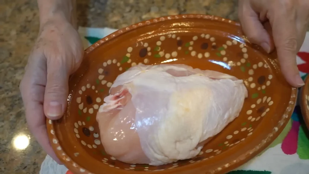 Raw chicken breast placed on a colorful ceramic plate, ready to be used for ensalada de pollo.