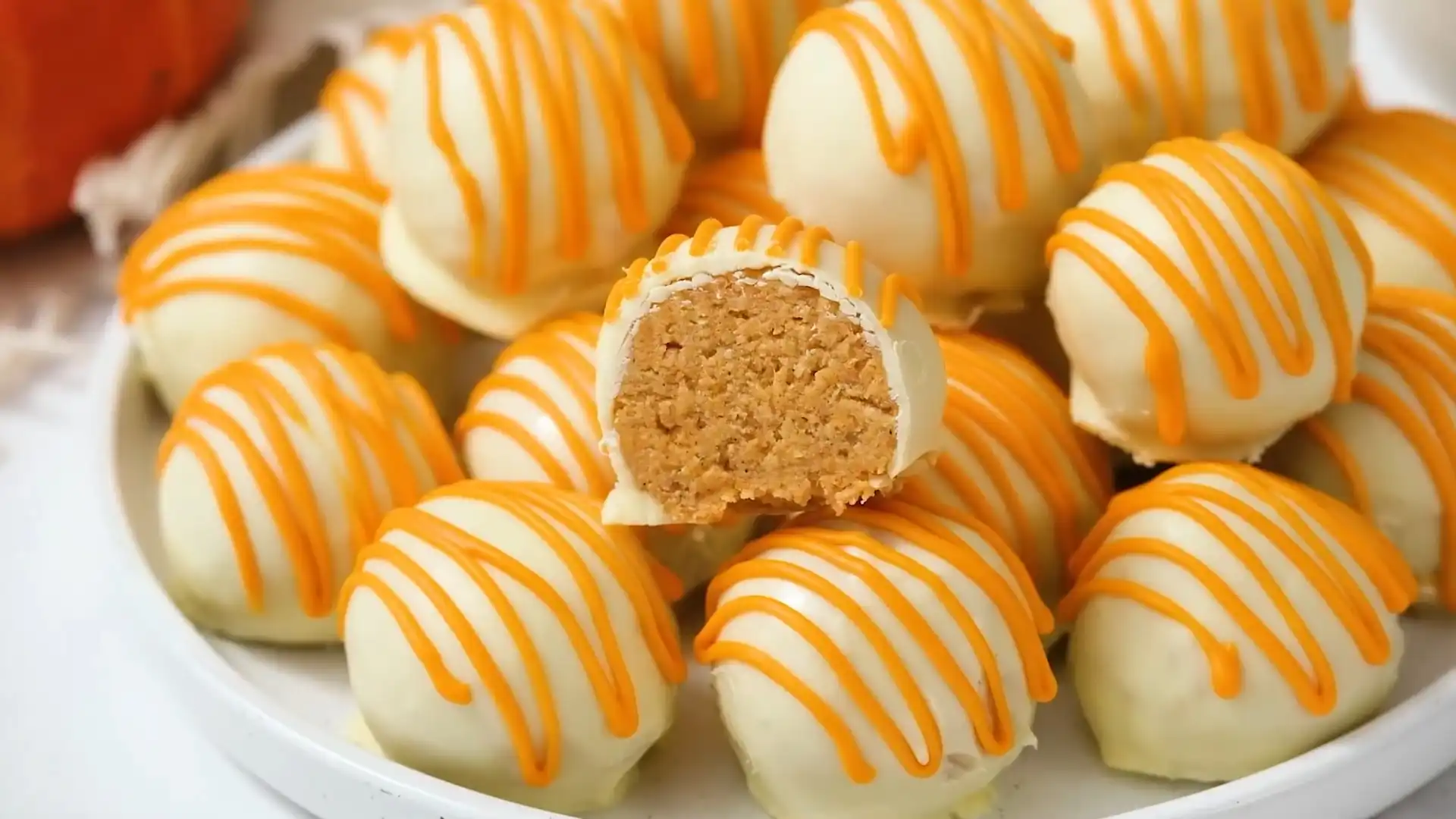 No-Bake Pumpkin Cheesecake Balls with white chocolate coating and orange drizzle