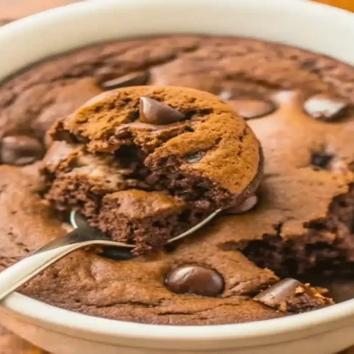 Delicious chocolate protein mug cake recipe served warm in a white mug with chocolate chips.